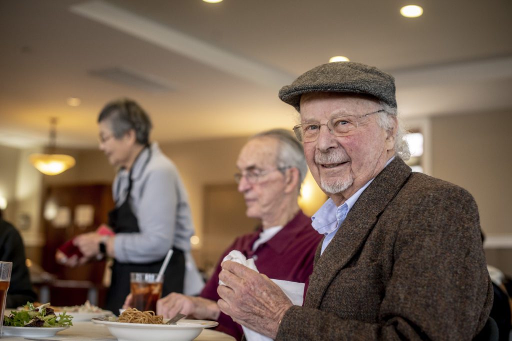 Senior man enjoys meal with friends