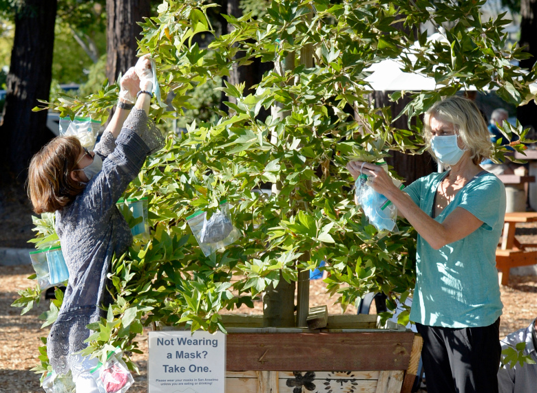 Two women putting masks on tree