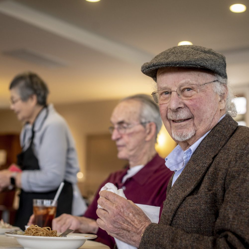 Senior man enjoys meal with friends (1)